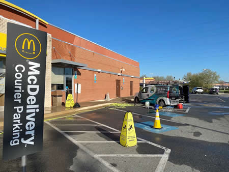 Technician using hot water surface cleaner on a stained sidewalk in shepherdstowns mcdonalds